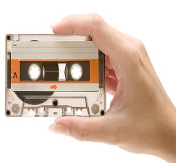 Female hand holding an old transparent audio cassette. White background.